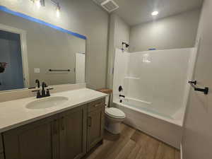 Bathroom featuring dark wood-type flooring, vanity, shower / tub combination, and recessed lighting