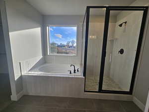 Bathroom featuring a garden tub, dark tile patterned floors, and a stall shower