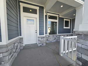 Entrance to property featuring stone siding and covered porch