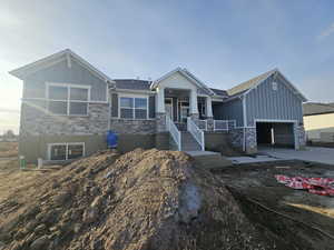 Craftsman inspired home with stone siding, board and batten siding, driveway, an attached garage, and a porch