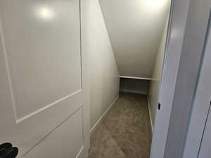 Corridor featuring a textured ceiling, carpet floors, and vaulted ceiling
