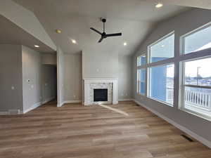 Unfurnished living room with lofted ceiling, light wood finished floors, ceiling fan, a fireplace, and recessed lighting