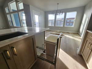 Kitchen featuring light wood finished floors, pendant lighting, and brown cabinetry