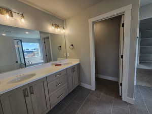 Full bath with double vanity, dark tile patterned flooring, and a textured ceiling