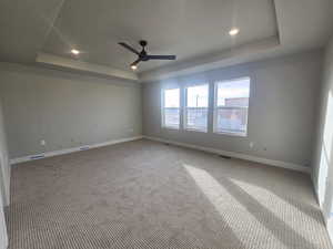 Carpeted spare room with a raised ceiling, recessed lighting, and ceiling fan