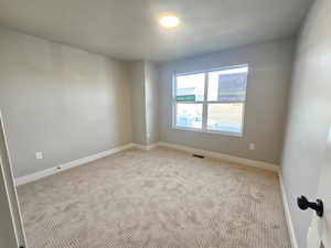 Carpeted spare room with baseboards and a textured ceiling