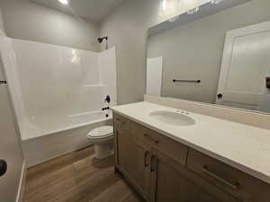 Bathroom with shower / washtub combination, vanity, and dark wood-style flooring