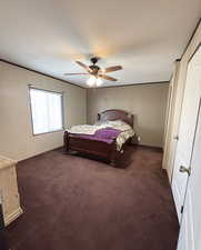 Bedroom featuring dark colored carpet, ceiling fan, and a closet