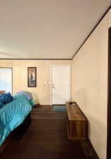 Bedroom featuring a decorative wall and dark wood-type flooring