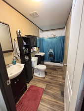 Full bathroom with vanity, wood finished floors, curtained shower, a textured ceiling, and ornamental molding