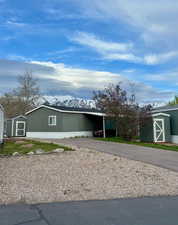 View of front of property featuring a shed, a mountain view, asphalt driveway, and a carport