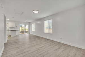 Unfurnished living room with baseboards and light wood-style flooring