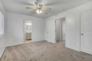 Unfurnished bedroom with light carpet, a ceiling fan, and connected bathroom