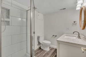 Full bathroom featuring vanity, a shower stall, light wood-style flooring, and a textured ceiling