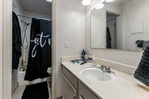 Bathroom with shower / tub combo with curtain, vanity, a textured wall, and light tile patterned flooring