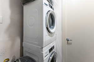 Laundry area featuring a textured wall and stacked washer and clothes dryer