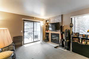 Carpeted living area featuring a fireplace with flush hearth