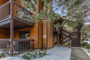 View of snowy exterior featuring stairway, a deck, and a balcony