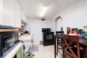 Kitchen featuring light countertops, white cabinetry, and black appliances