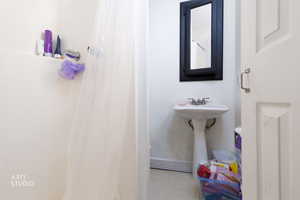 Bathroom with a shower with curtain and tile patterned flooring