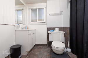 Bathroom featuring vanity, tile walls, wainscoting, and a shower with shower curtain