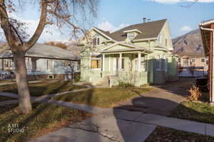 View of front of property featuring a front yard, stucco siding, a shingled roof, and a porch