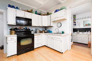 Kitchen with black appliances, white cabinetry, and light countertops