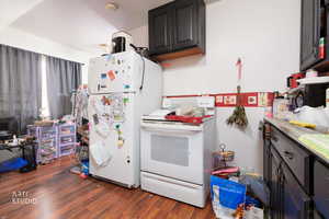 Kitchen featuring white appliances, dark wood-style floors, and light countertops
