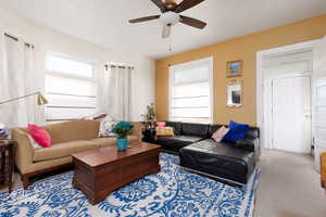 Living room with plenty of natural light, a ceiling fan, and carpet