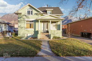 View of front of property with a shingled roof, a front yard, a porch, and a mountain view