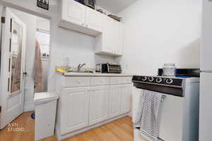 Kitchen featuring white cabinets, light countertops, and light wood finished floors