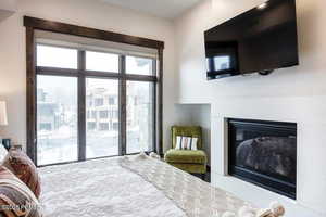 Bedroom featuring a glass covered fireplace and access to outside