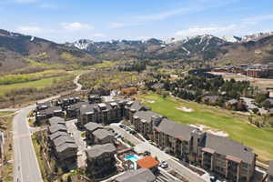 Community of multi-story buildings with balconies, featuring an outdoor pool and adjacent golf course