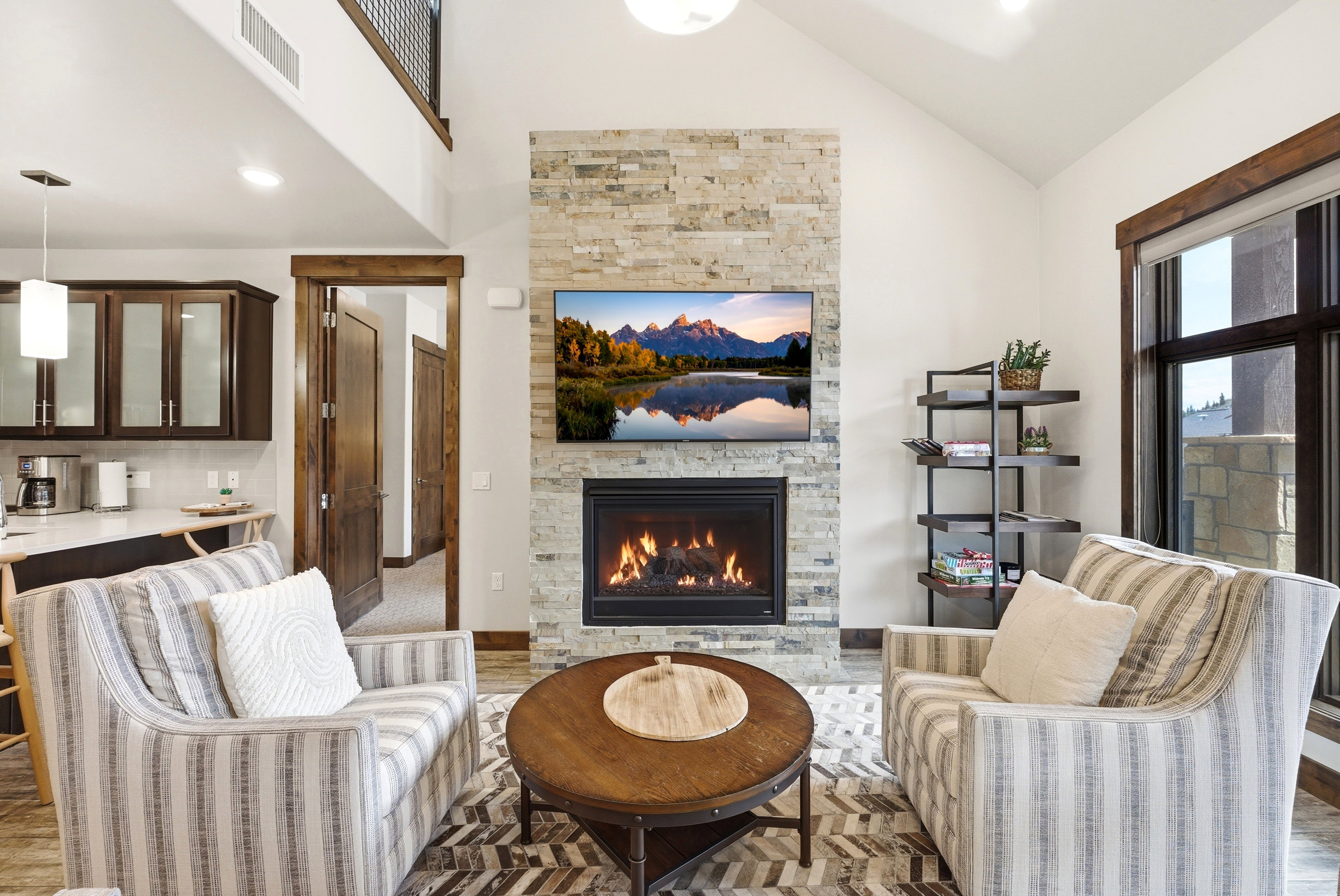 Living area featuring a stone-clad fireplace, vaulted ceilings, and wood-finish flooring