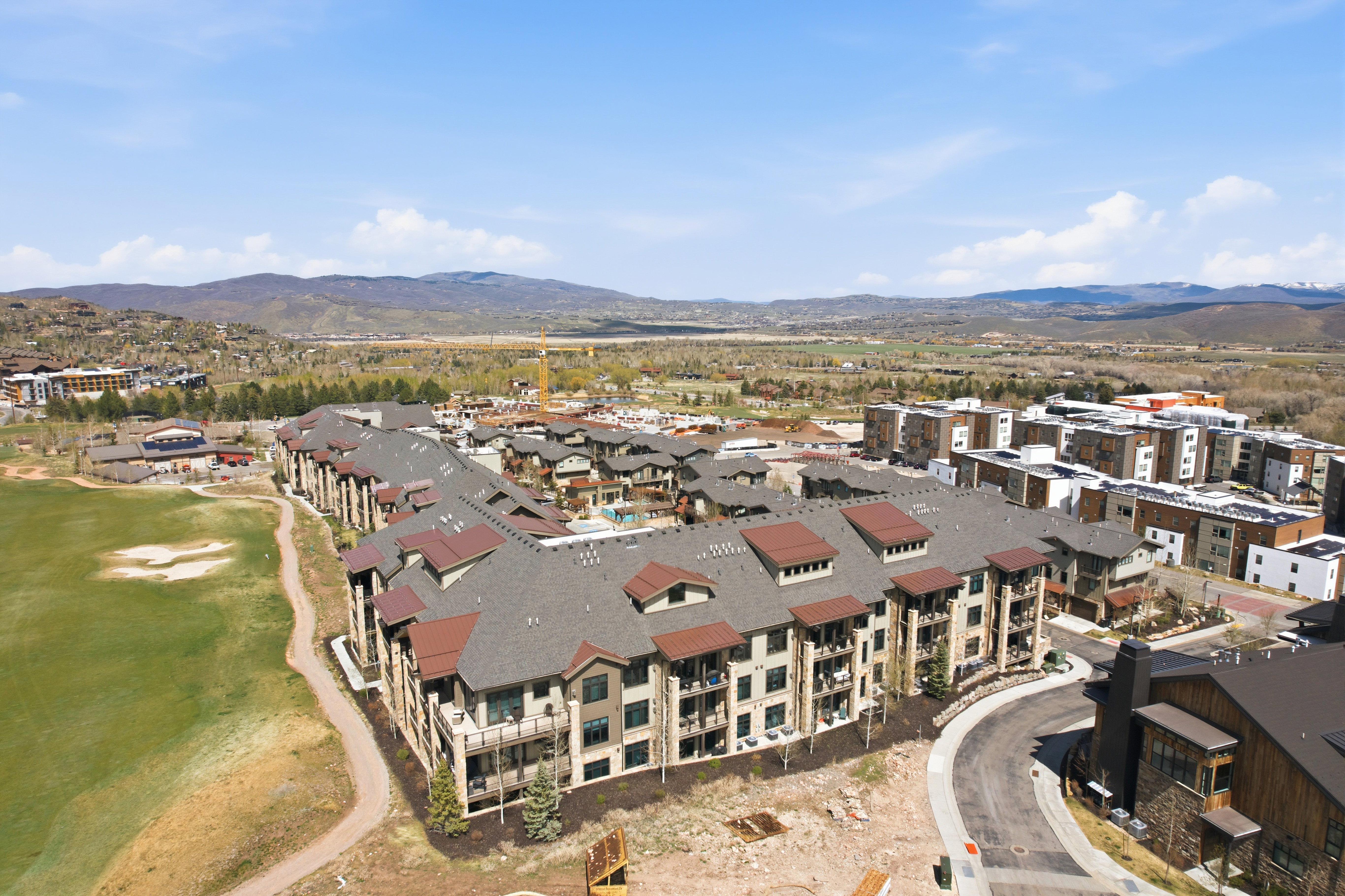 Contemporary multi-story residential building with private balconies and a brown shingle roof