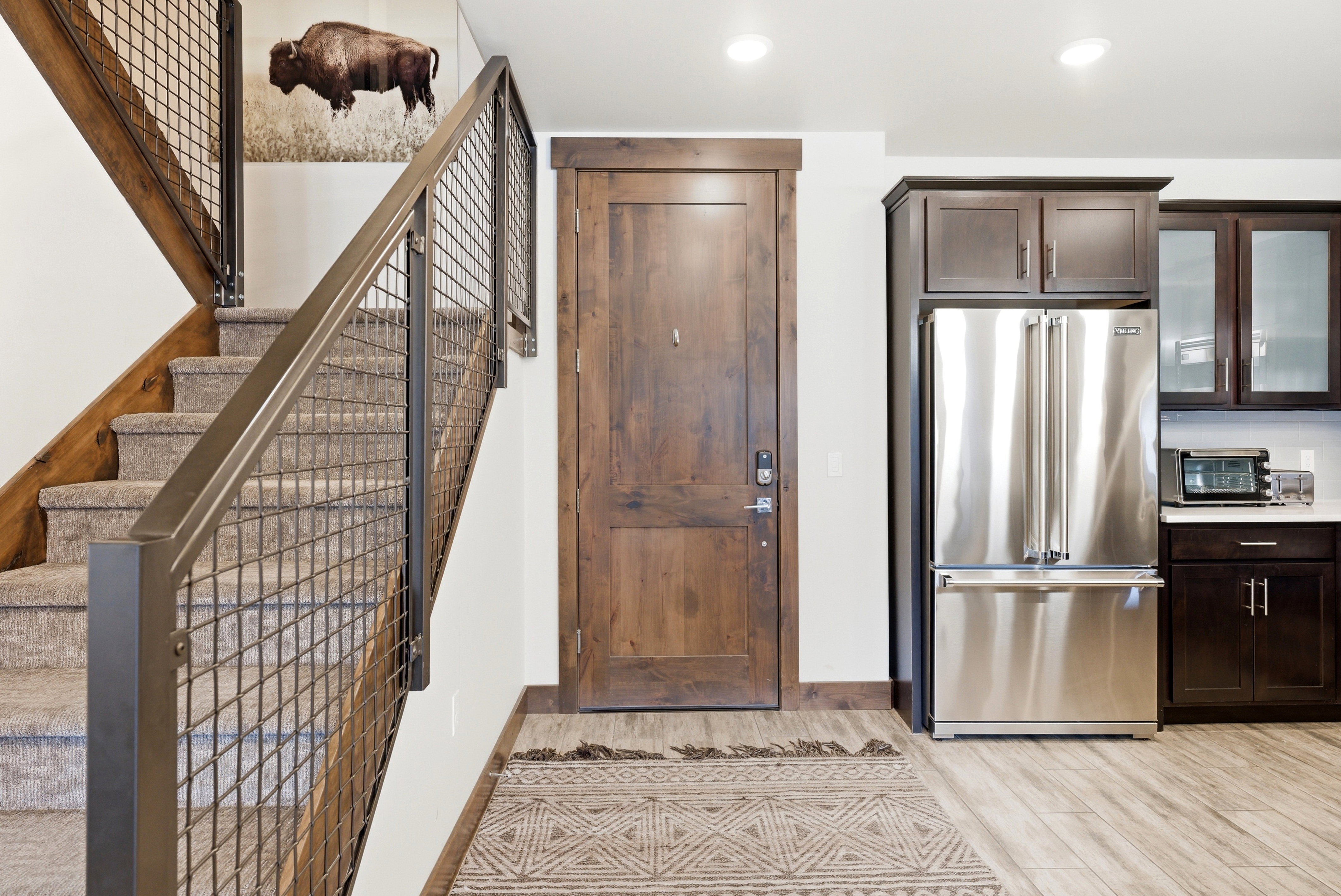 Staircase with industrial-style metal grid railing and wood-finish handrail