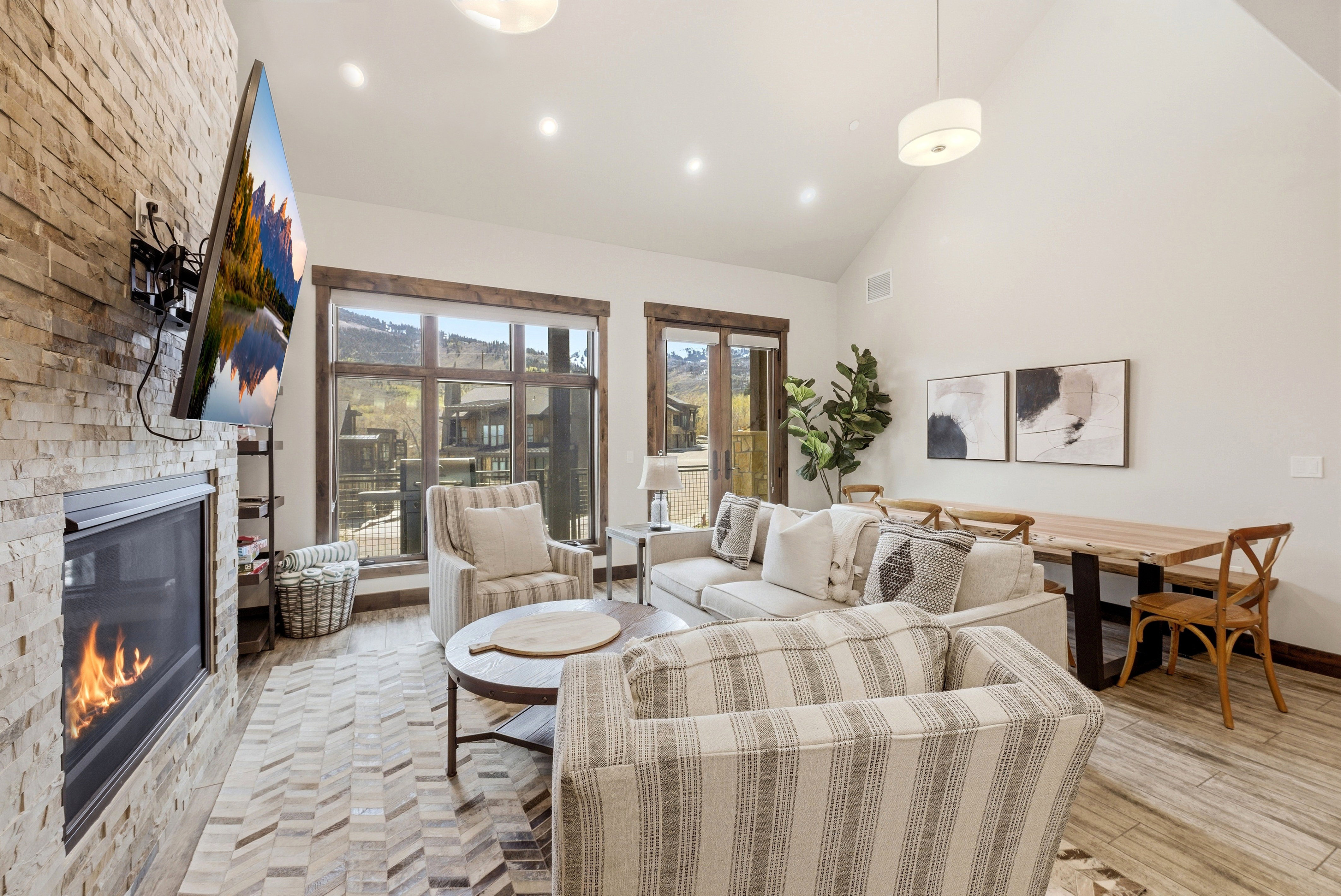 Spacious living area featuring a stone-clad fireplace and large picture windows