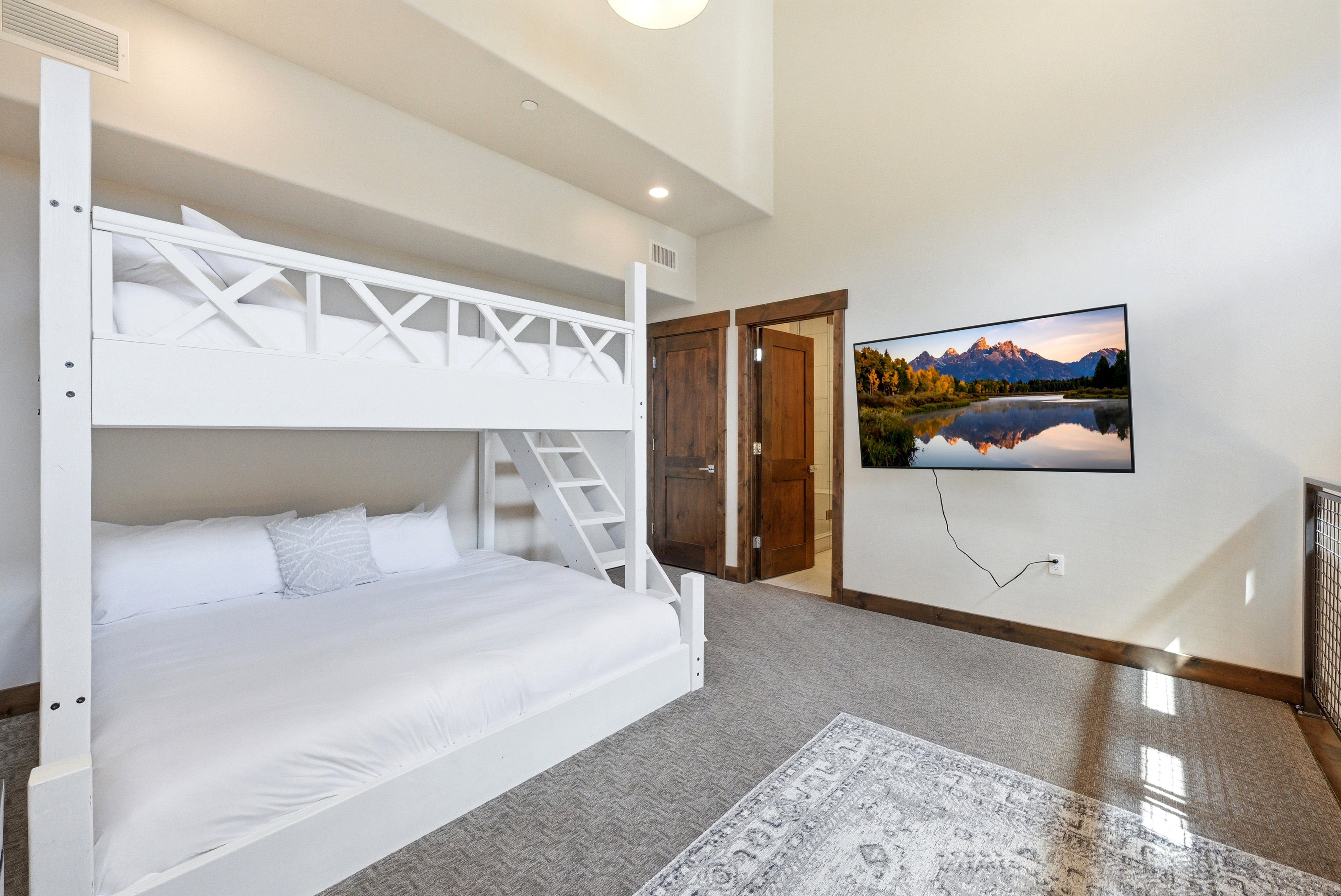 White bunk bed with a built-in ladder, wood-finish doors, high ceilings, recessed lighting, and a wall-mounted television