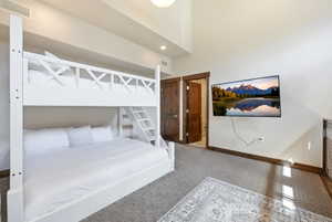 White bunk bed with a built-in ladder, wood-finish doors, high ceilings, recessed lighting, and a wall-mounted television