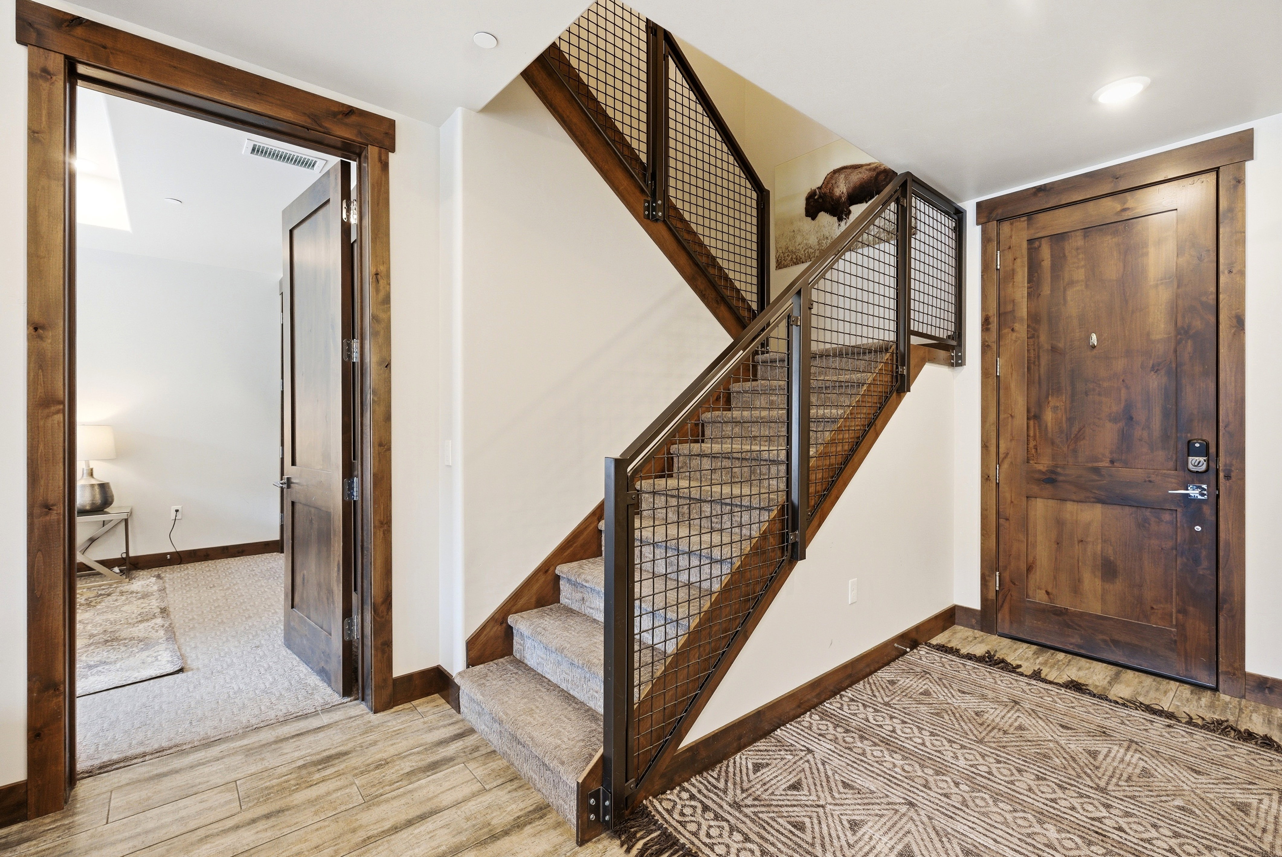 Staircase featuring wood treads, industrial-style metal railing, and carpeted steps