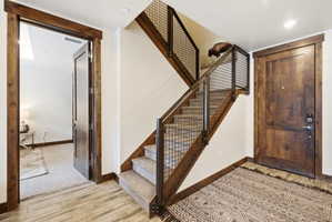 Staircase featuring wood treads, industrial-style metal railing, and carpeted steps