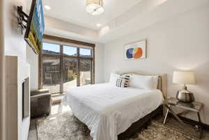 Bedroom featuring a built-in fireplace, large picture window with wooden framing, and recessed ceiling lighting