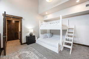 Carpeted bedroom with recessed lighting and a towering ceiling