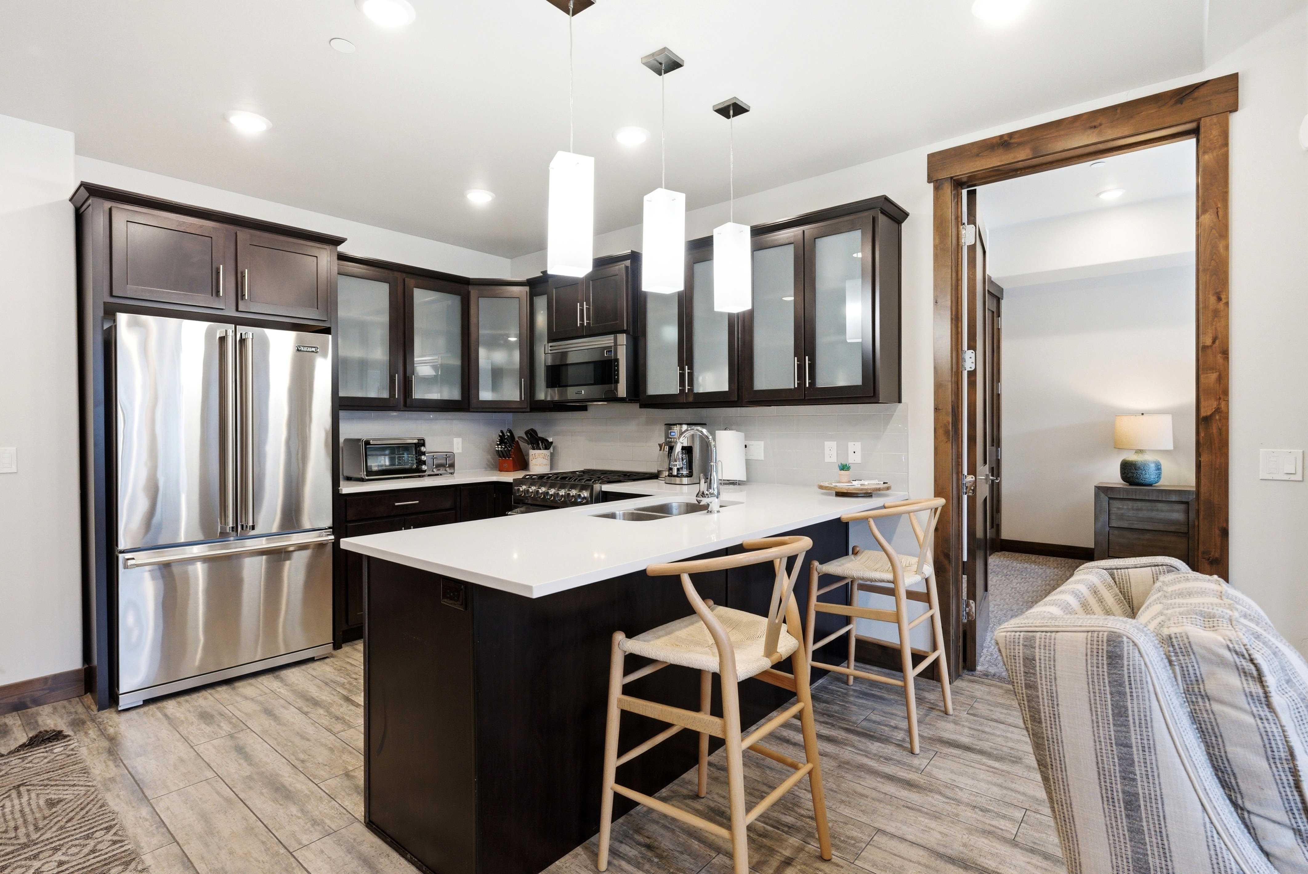Modern kitchen featuring dark wood cabinetry, stainless steel appliances, a center island with a white countertop, and recessed lighting