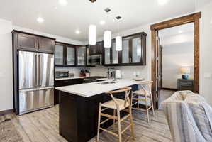 Modern kitchen featuring dark wood cabinetry, stainless steel appliances, a center island with a white countertop, and recessed lighting