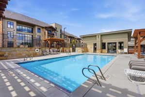 Outdoor swimming pool featuring a perimeter concrete deck, integrated steps, and stainless steel handrails