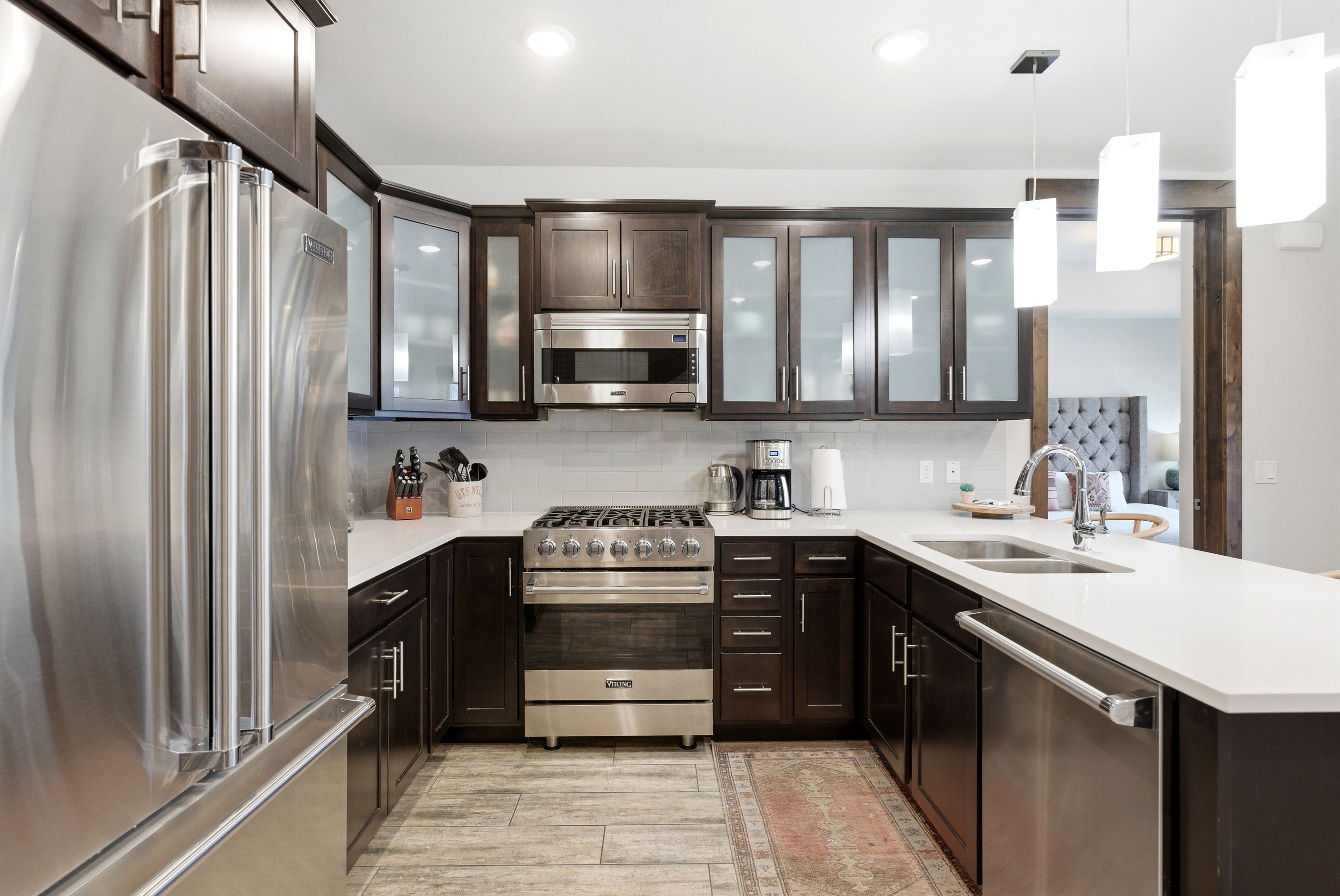 Modern kitchen featuring dark wood cabinetry, stainless steel appliances, white countertops, and a subway tile backsplash