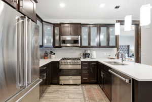Modern kitchen featuring dark wood cabinetry, stainless steel appliances, white countertops, and a subway tile backsplash
