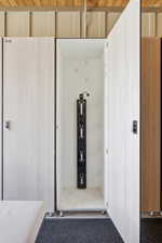 Individual locker storage featuring wood-finish paneling, an integrated hanging system, and a durable mat flooring