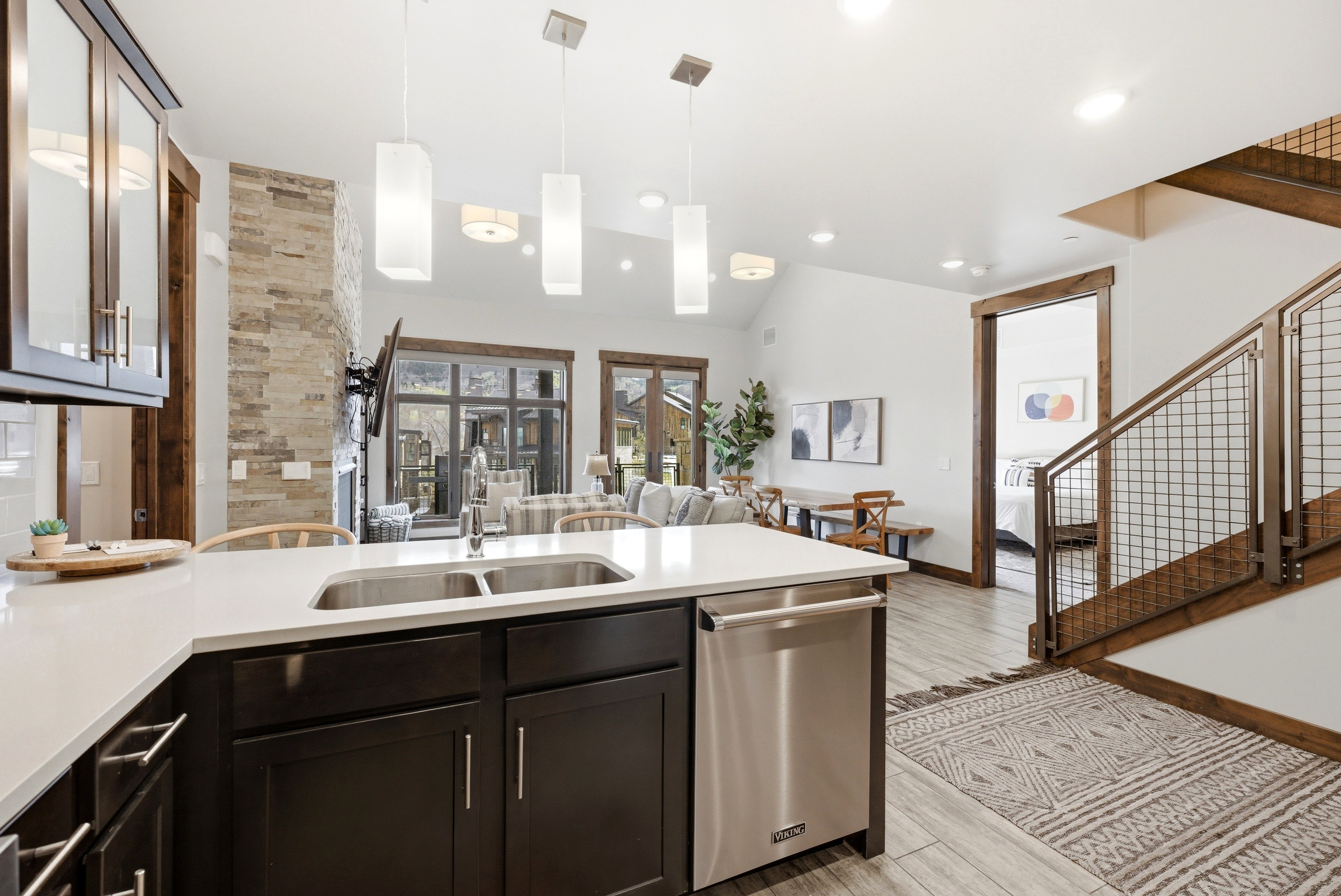 Modern kitchen island featuring a double stainless steel sink, a stainless steel dishwasher, and white countertops
